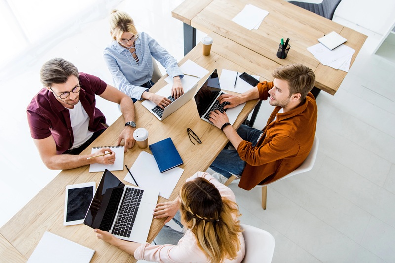 An overhead view of a team working together around a table with laptops
